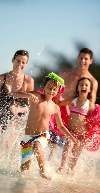 family running on the beach water in swimwear