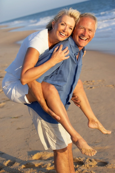 Happy senior couple at the beach man carrying woman